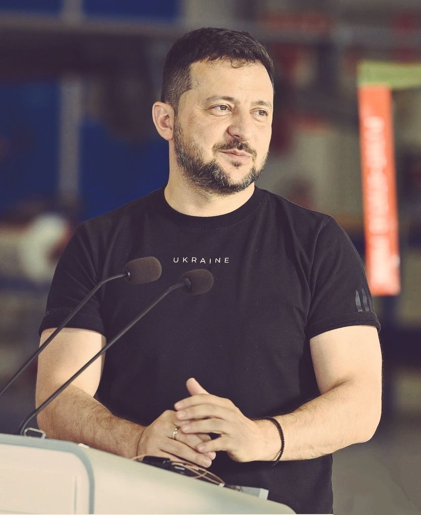 ภาพของโวโลดีเมียร์ เซเลนสกี ประธานาธิบดียูเครน สวมเสื้อยืดสีดำพร้อมคำว่า"UKRAINE" ขณะพูดที่โพเดียม