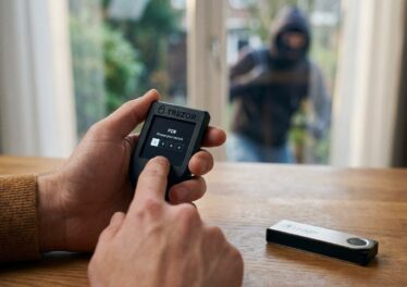 ภาพคนกำลังใช้งาน Hardware Wallet ในบ้าน แล้วมีโจรย่องอยู่นอกบ้านลาง ๆ โดยZoom ให้เห็นว่ามือกำลังกด Hardware Wallet อยู่จริง ๆ