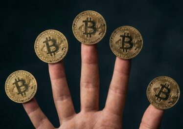 เหรียญ Bitcoin วางบนปลายนิ้วทั้งห้า สื่อถึง 5 ปัจจัยที่ดันราคาขึ้น